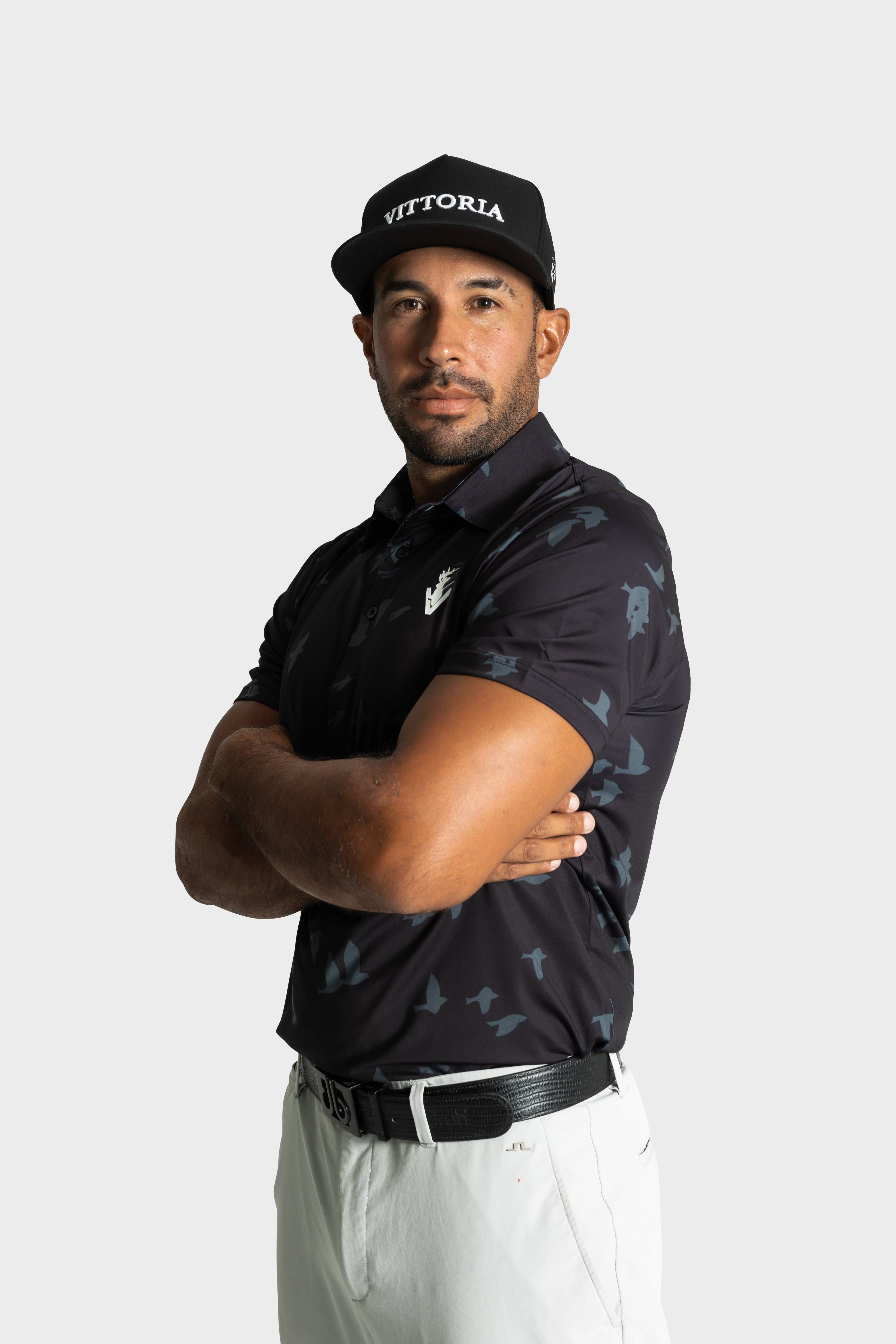 Man wearing The Flock polo by VittoriaGolfco with bird pattern and black cap