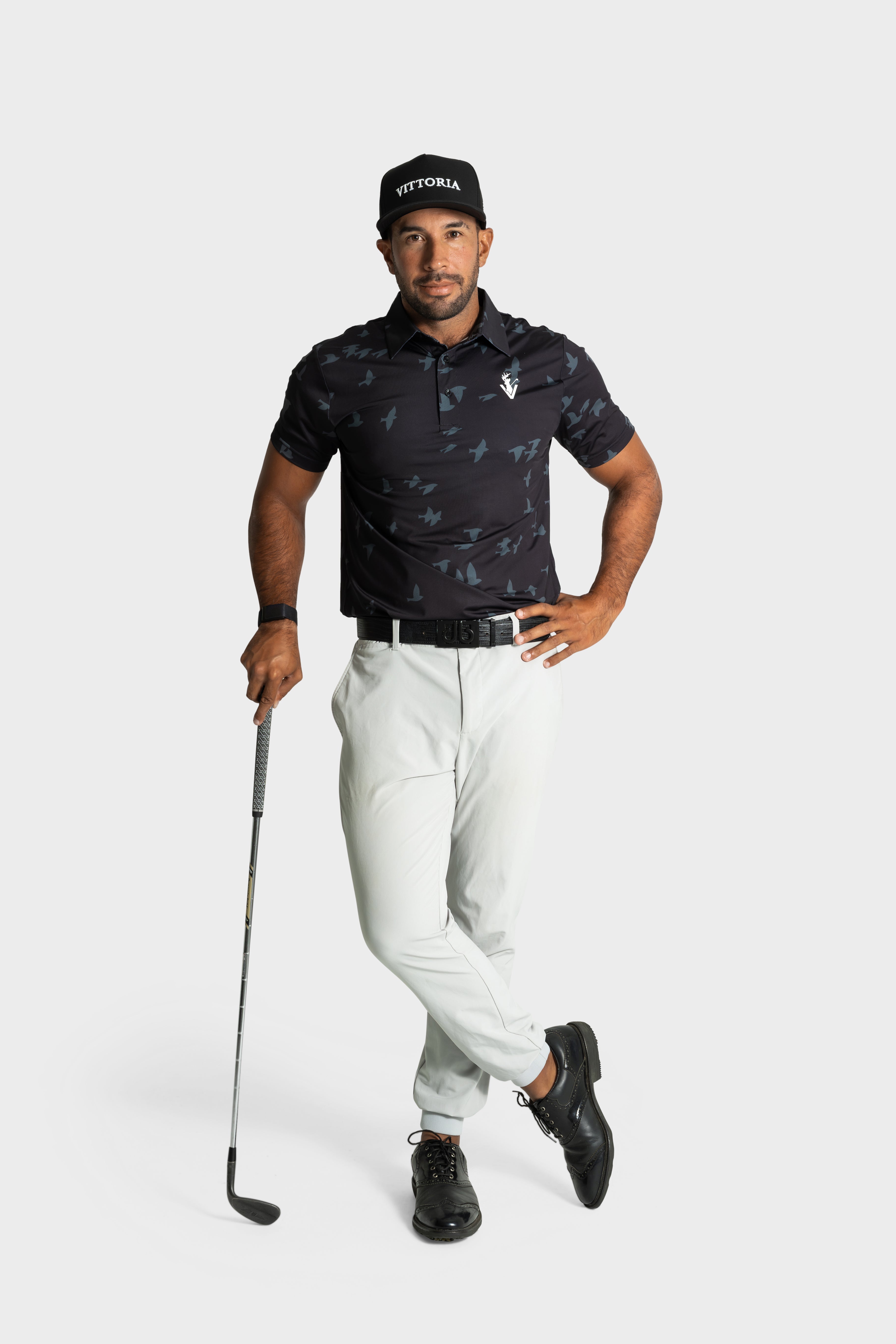 Man wearing The Flock polo by VittoriaGolfco with golf club on white background