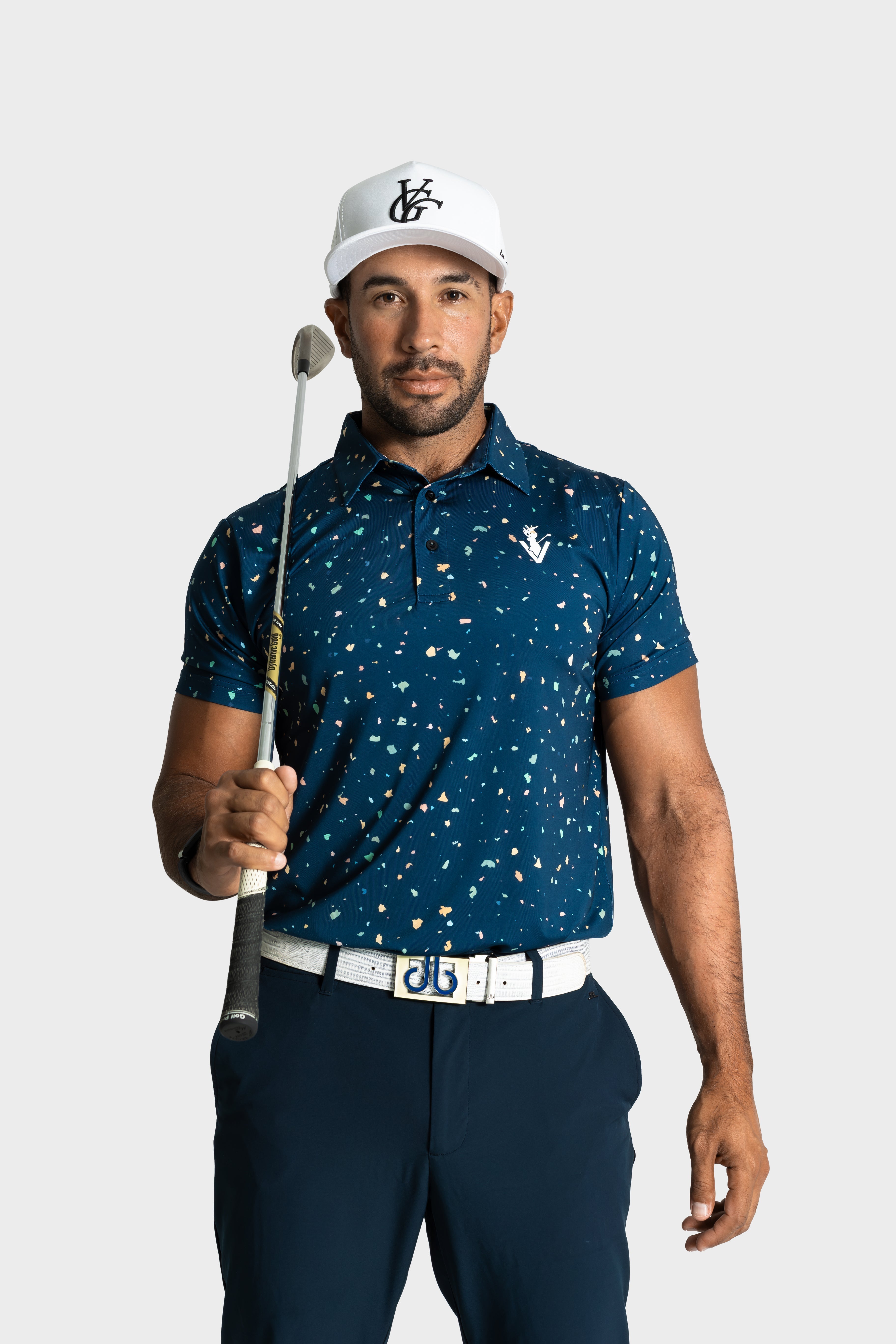 Male golfer wearing The Underlay polo by VittoriaGolfco holding golf club in blue patterned shirt and white cap