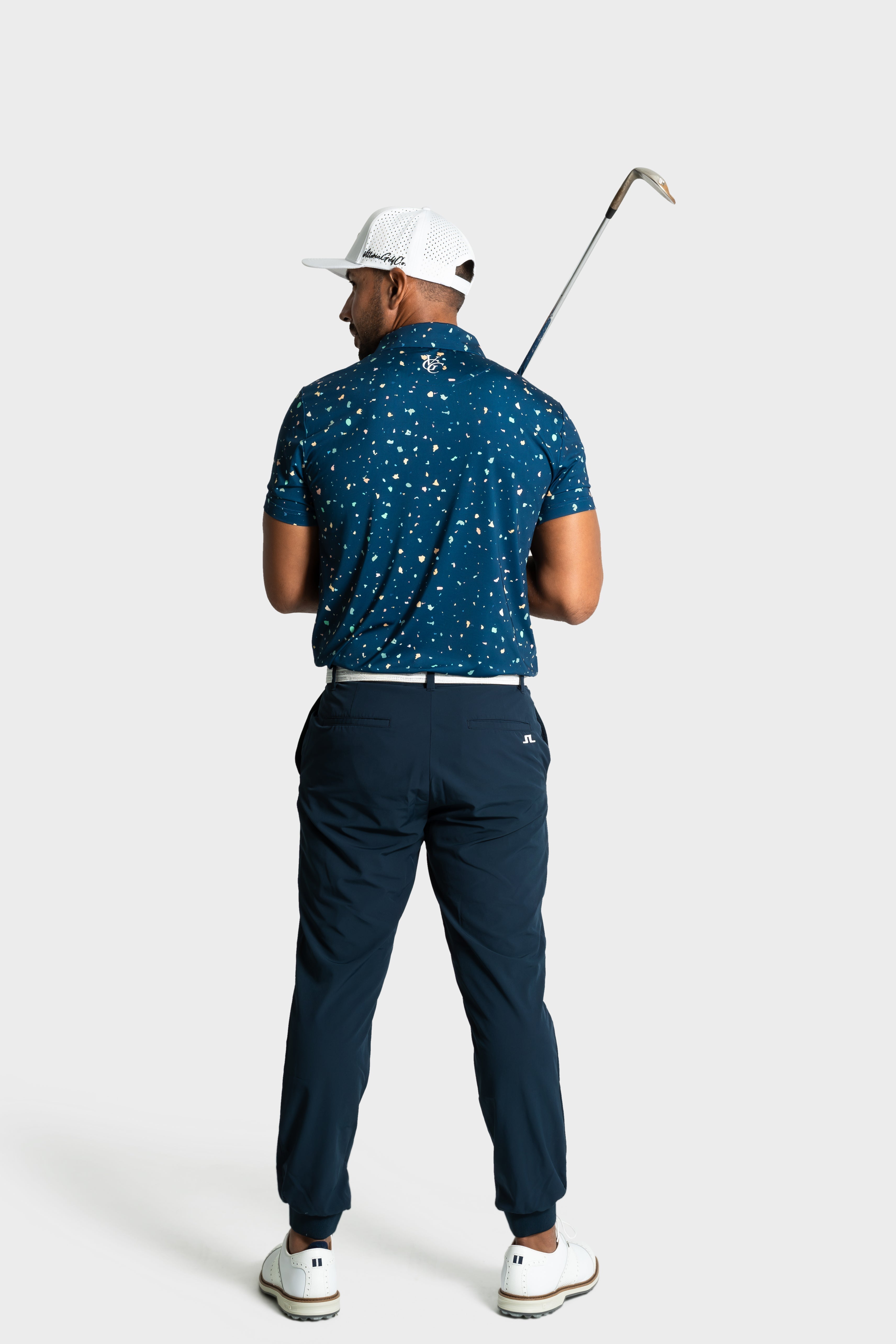 Man wearing The Underlay polo by VittoriaGolfco in blue patterned design holding golf club