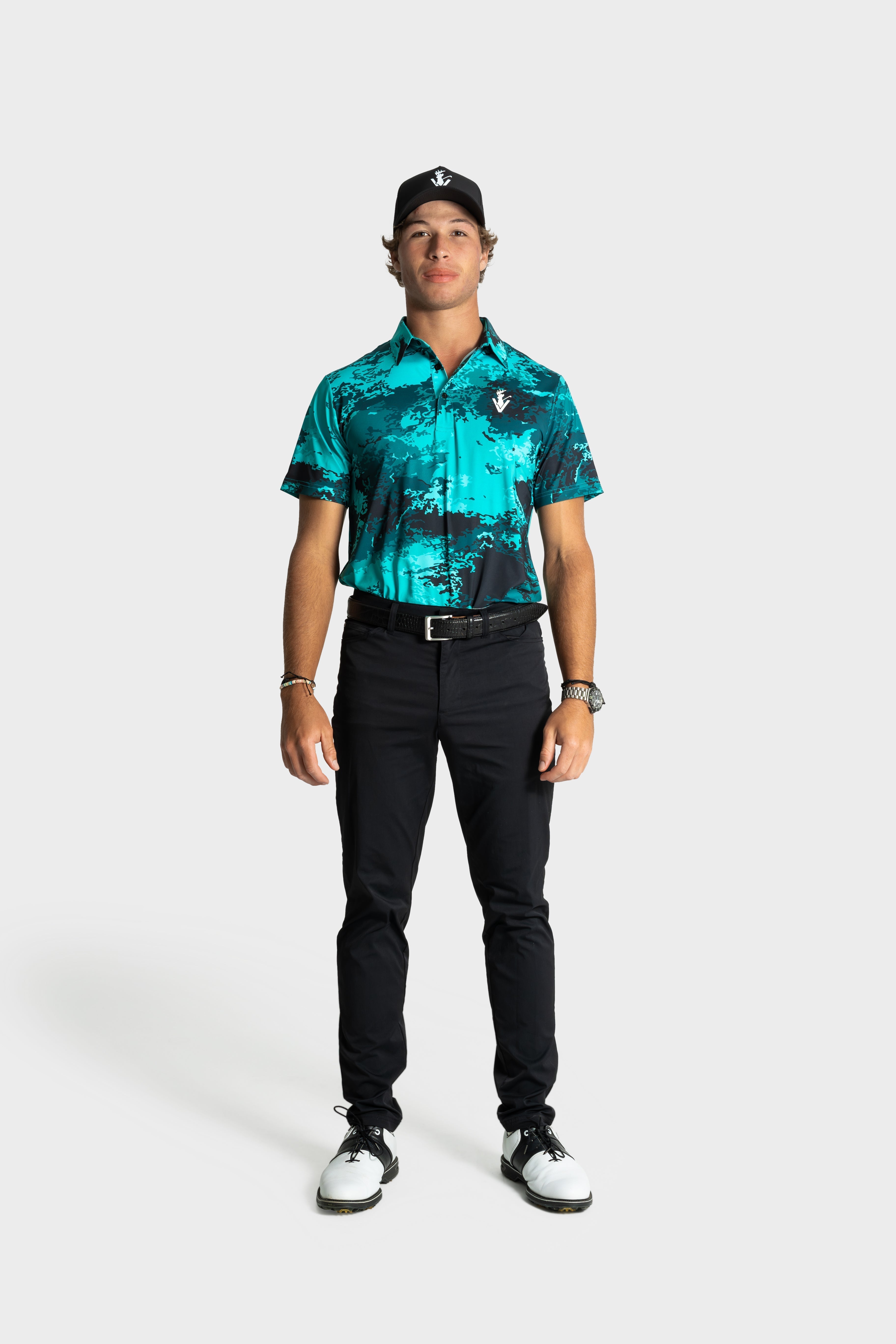 Man wearing The One polo by VittoriaGolfco in teal and black pattern with black pants and golf cap