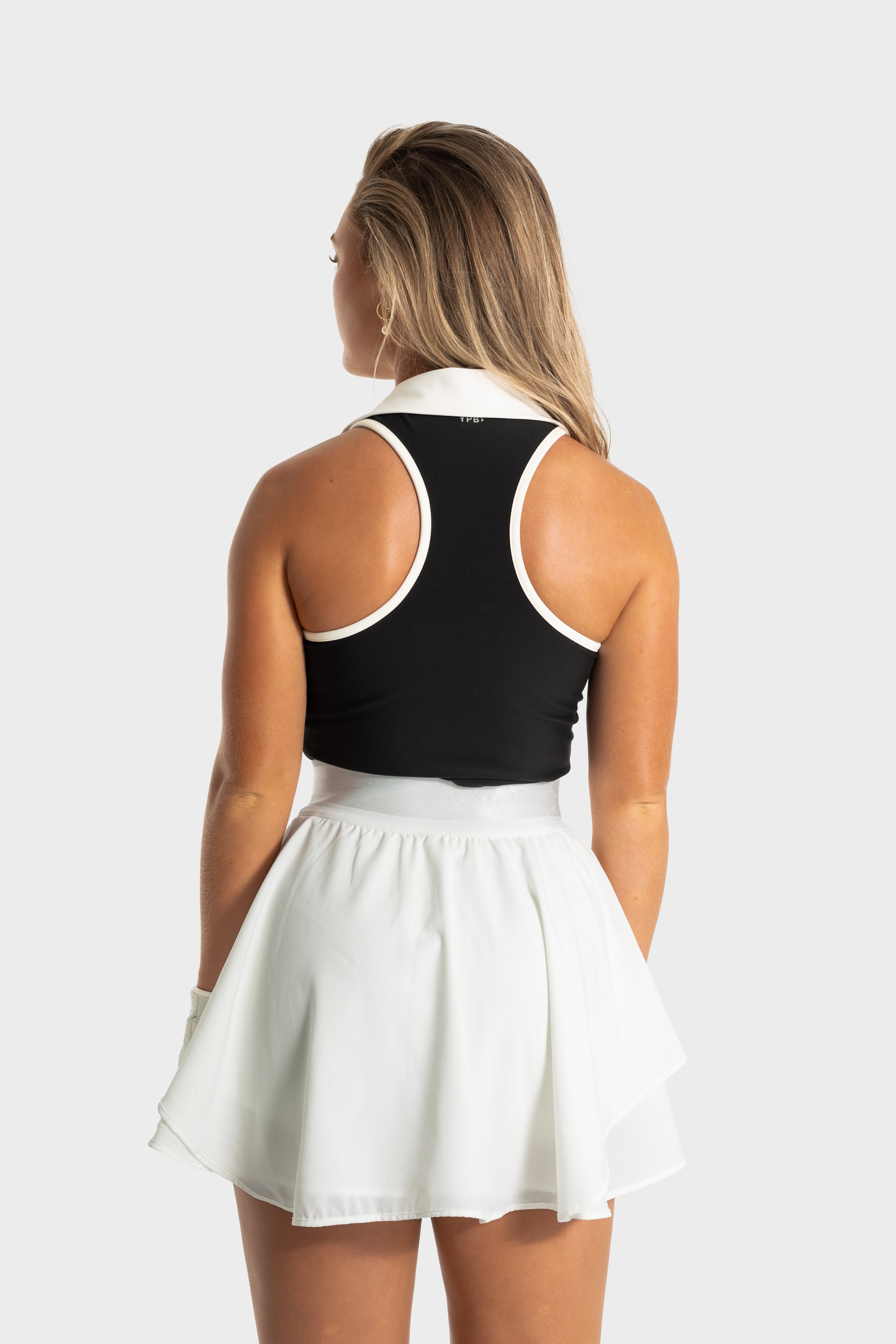 Woman wearing white Blossom golf skirt by Vittoria Golf Co, back view