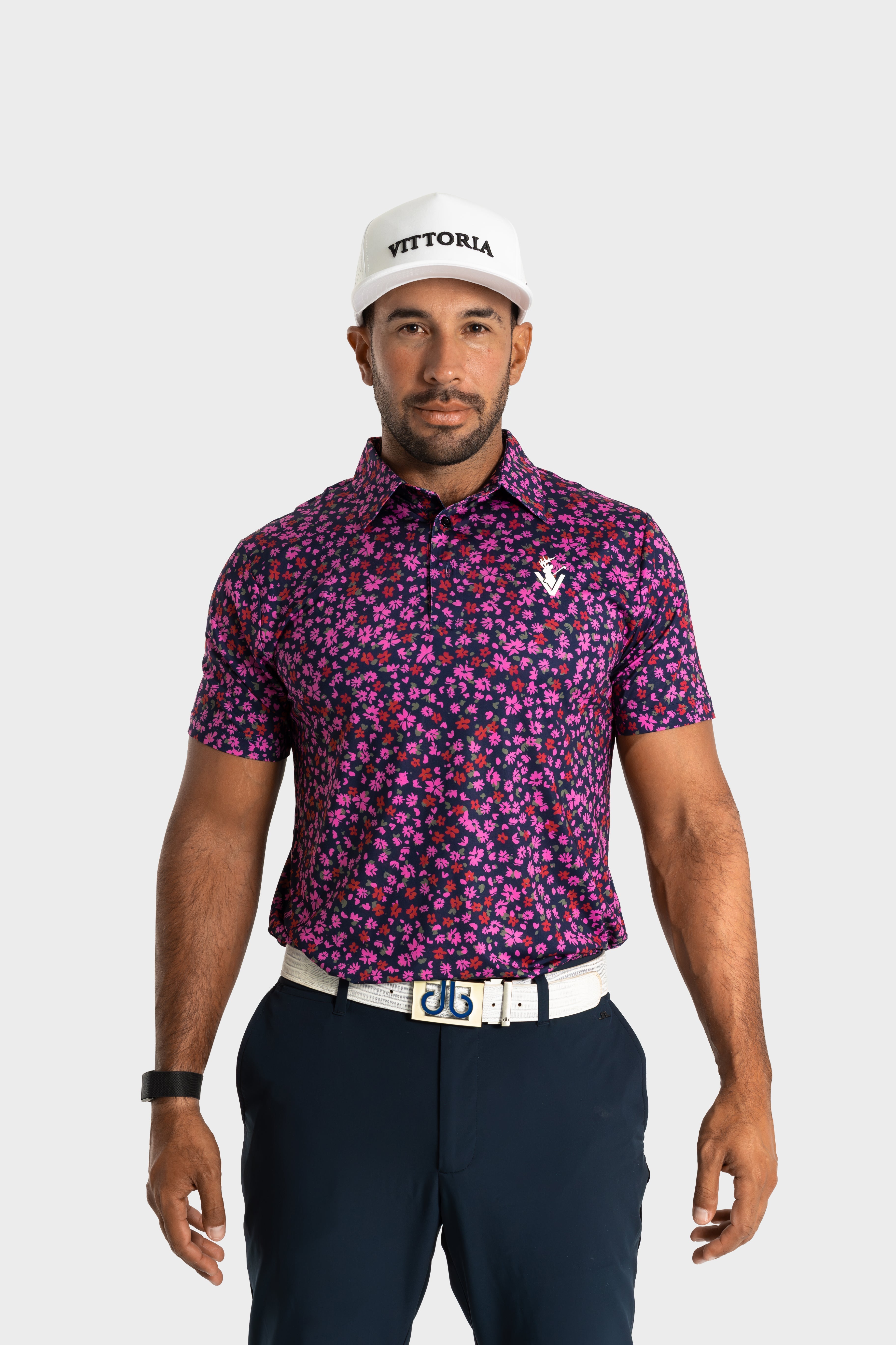 Man wearing The Secret Garden floral print polo shirt by VittoriaGolfco with navy pants and white cap