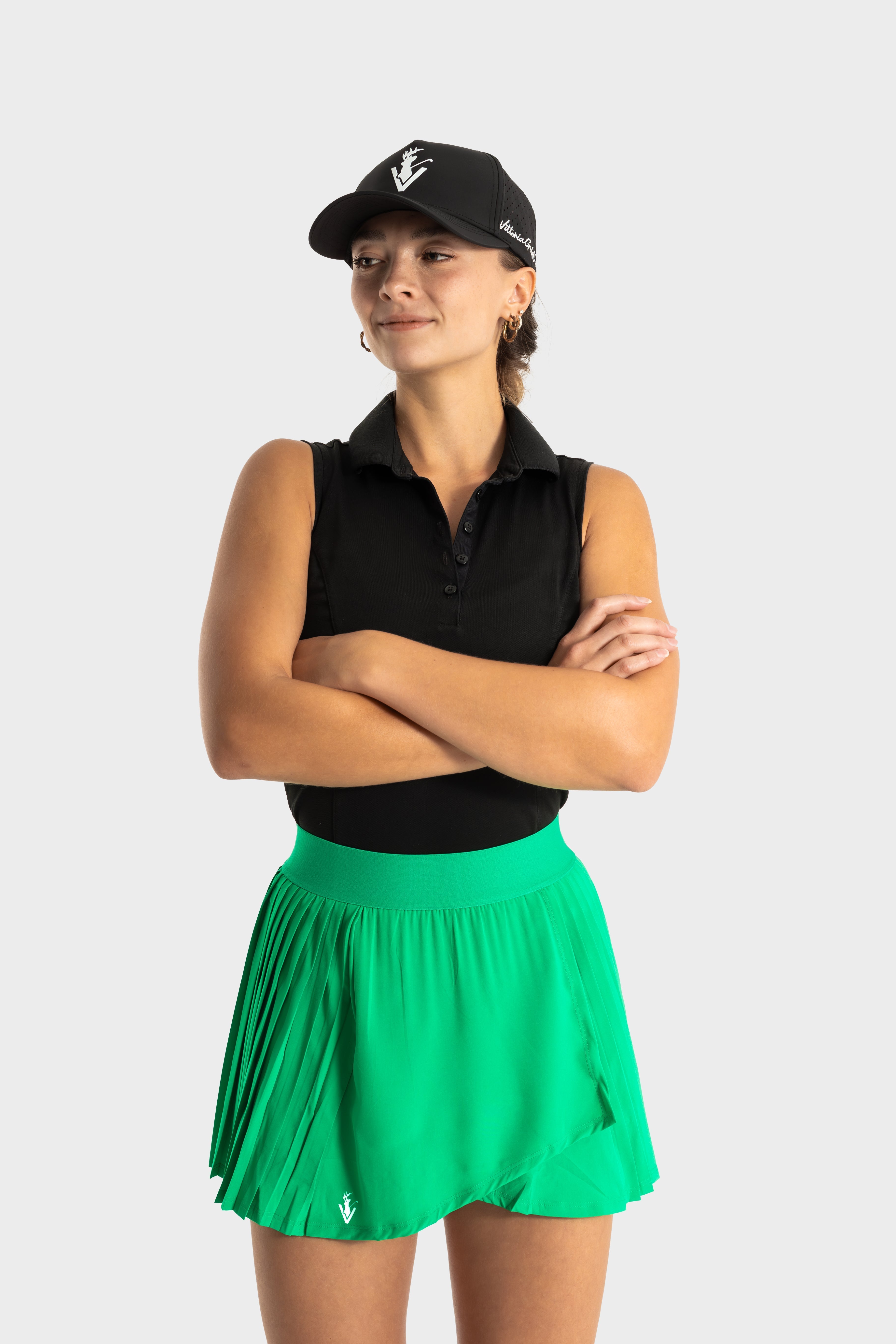 Woman wearing Perfetta golf skirt in green with black polo and cap