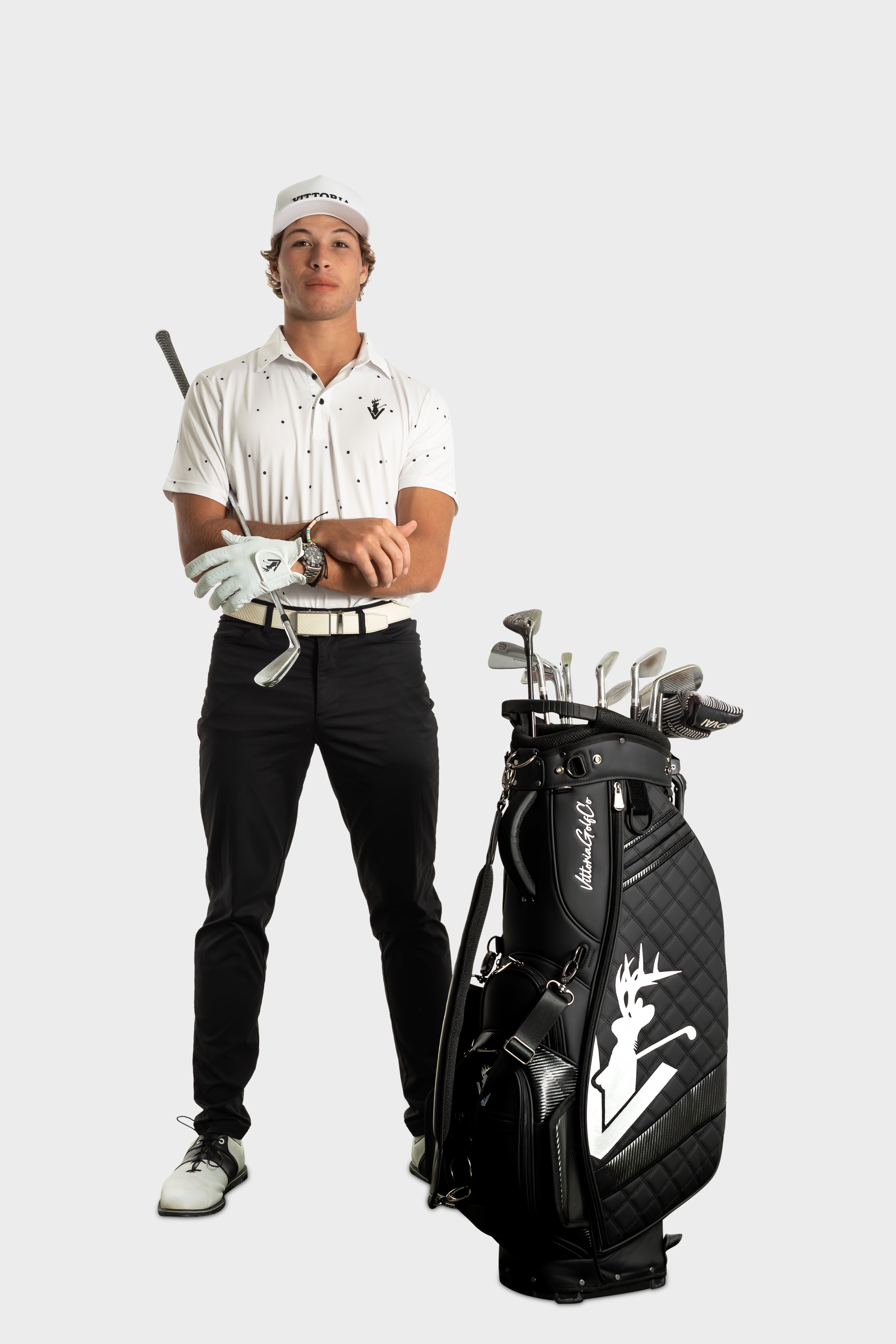 Male golfer wearing The Hinson polo standing next to a golf bag with clubs