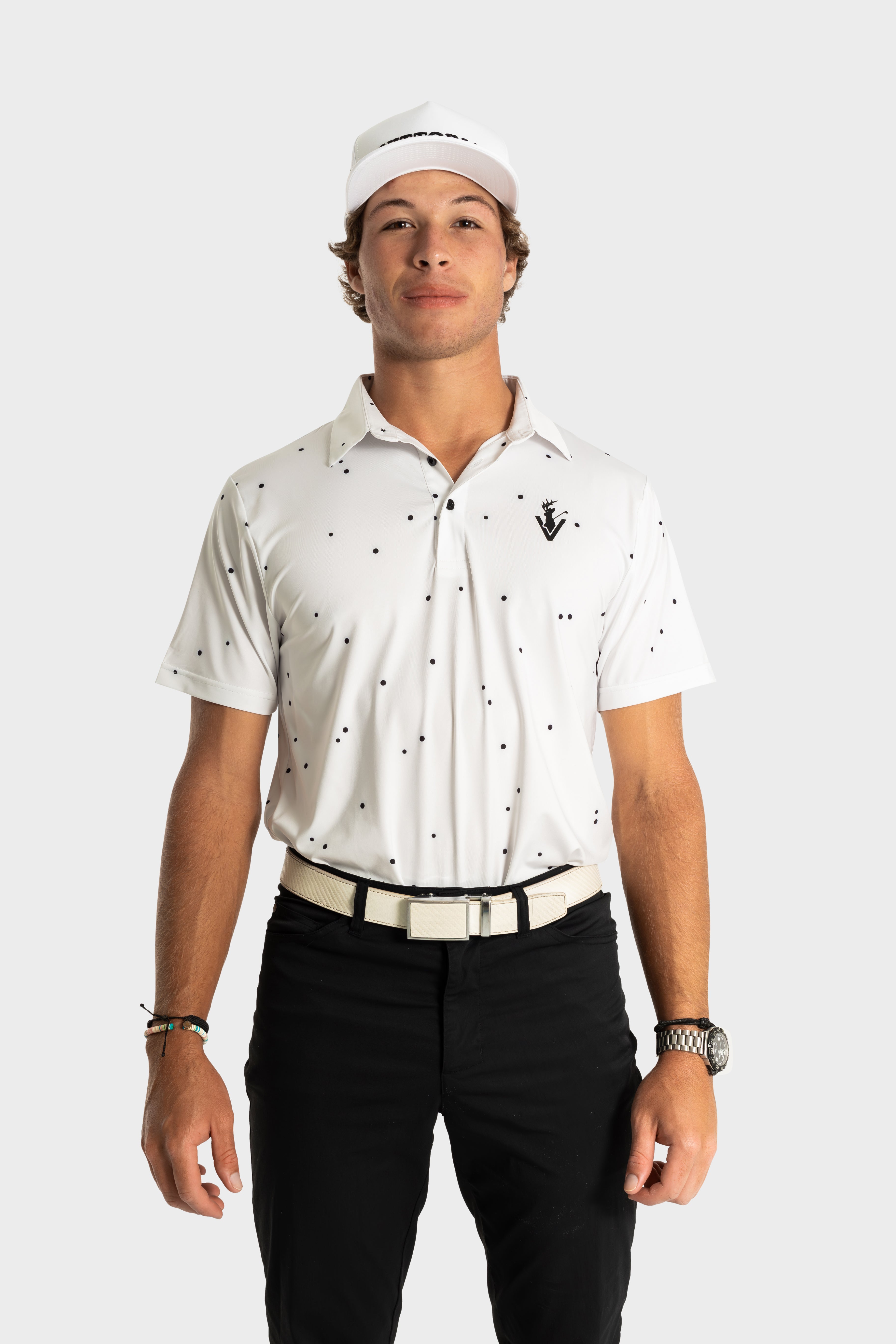 Man wearing The Hinson polo white shirt with black dots and black pants, styled for golf.