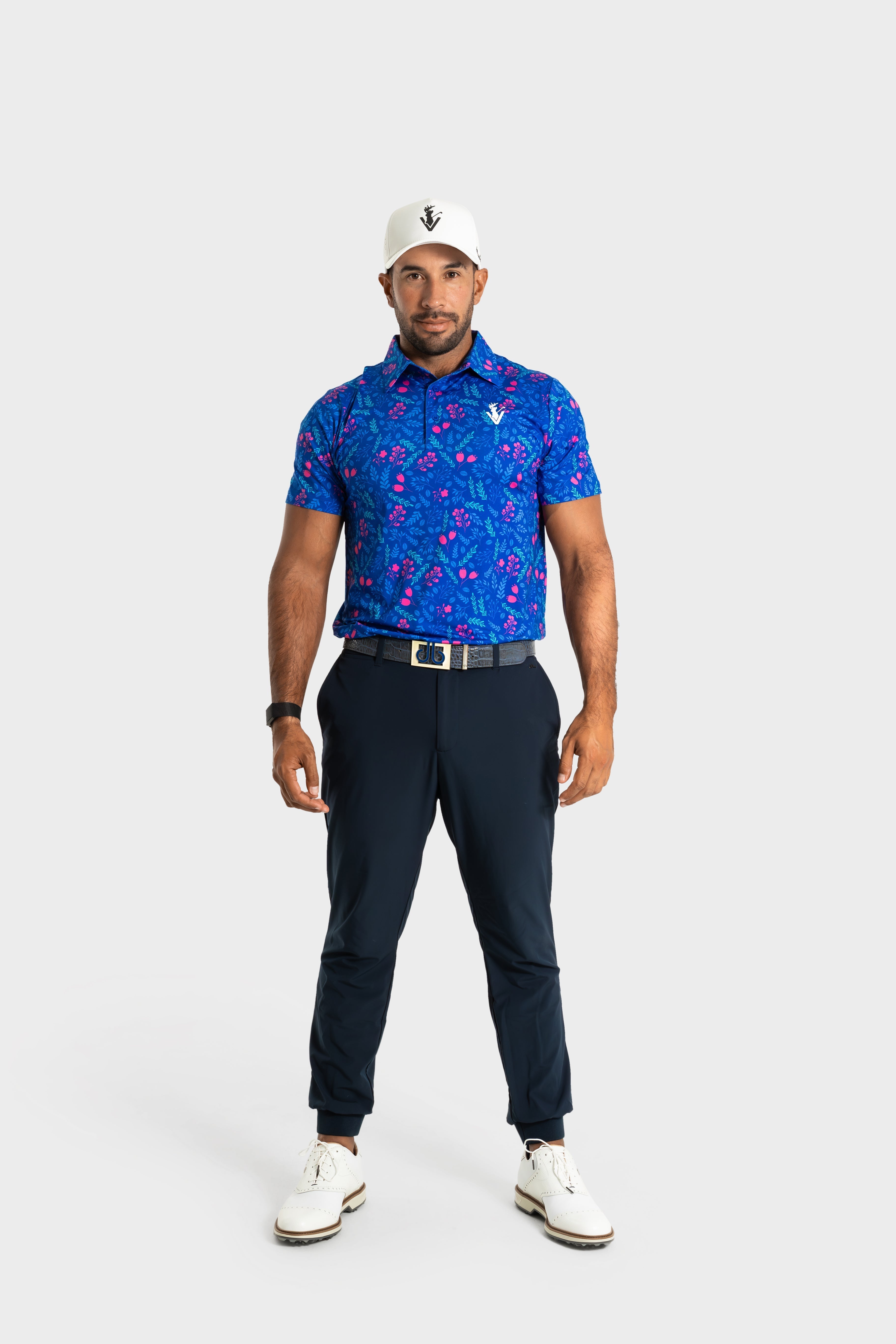 The Gatsby polo by VittoriaGolfco in blue with pink pattern worn by male golfer with white cap and black pants