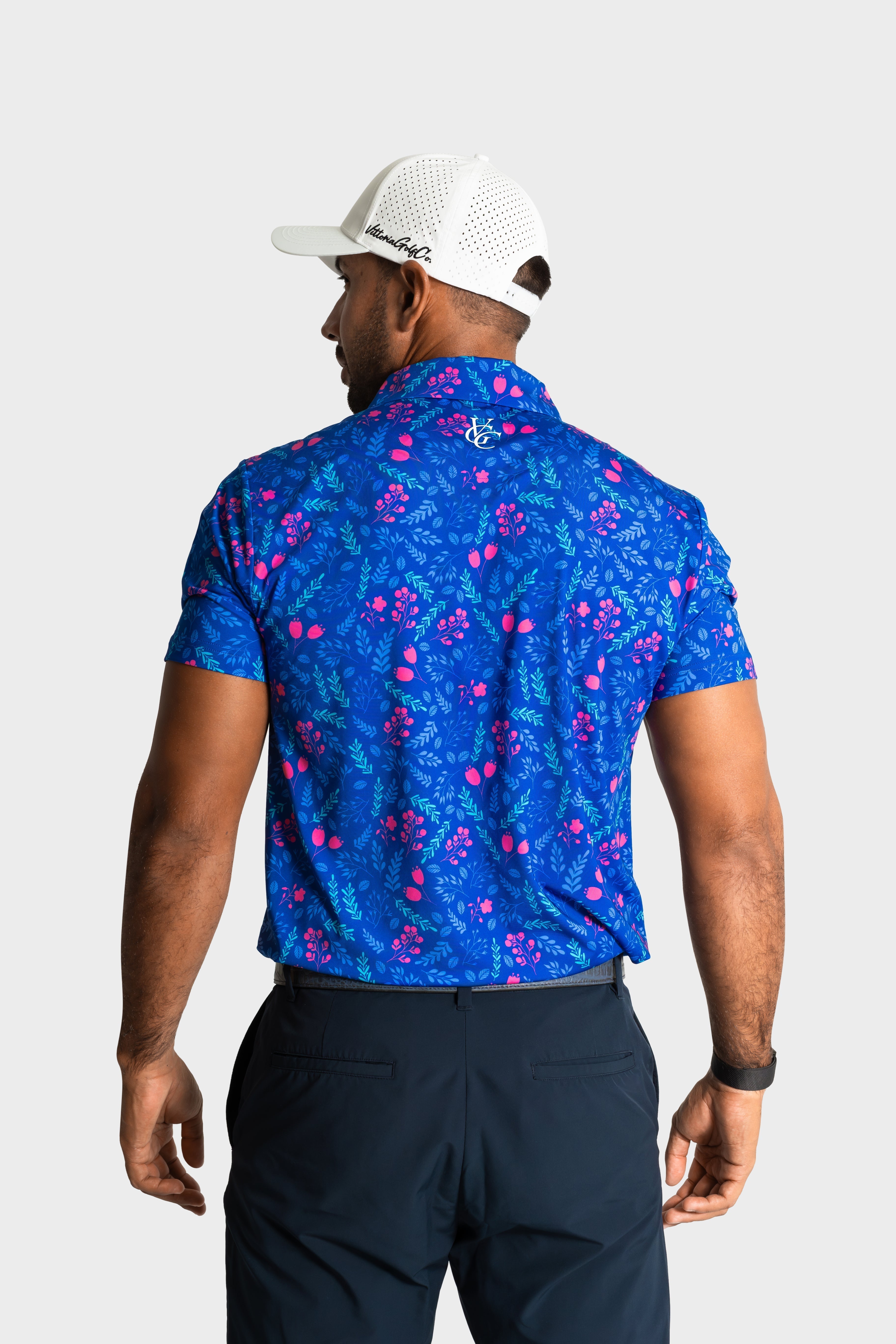 The Gatsby polo featuring a blue floral pattern worn by a man from the back with a white cap