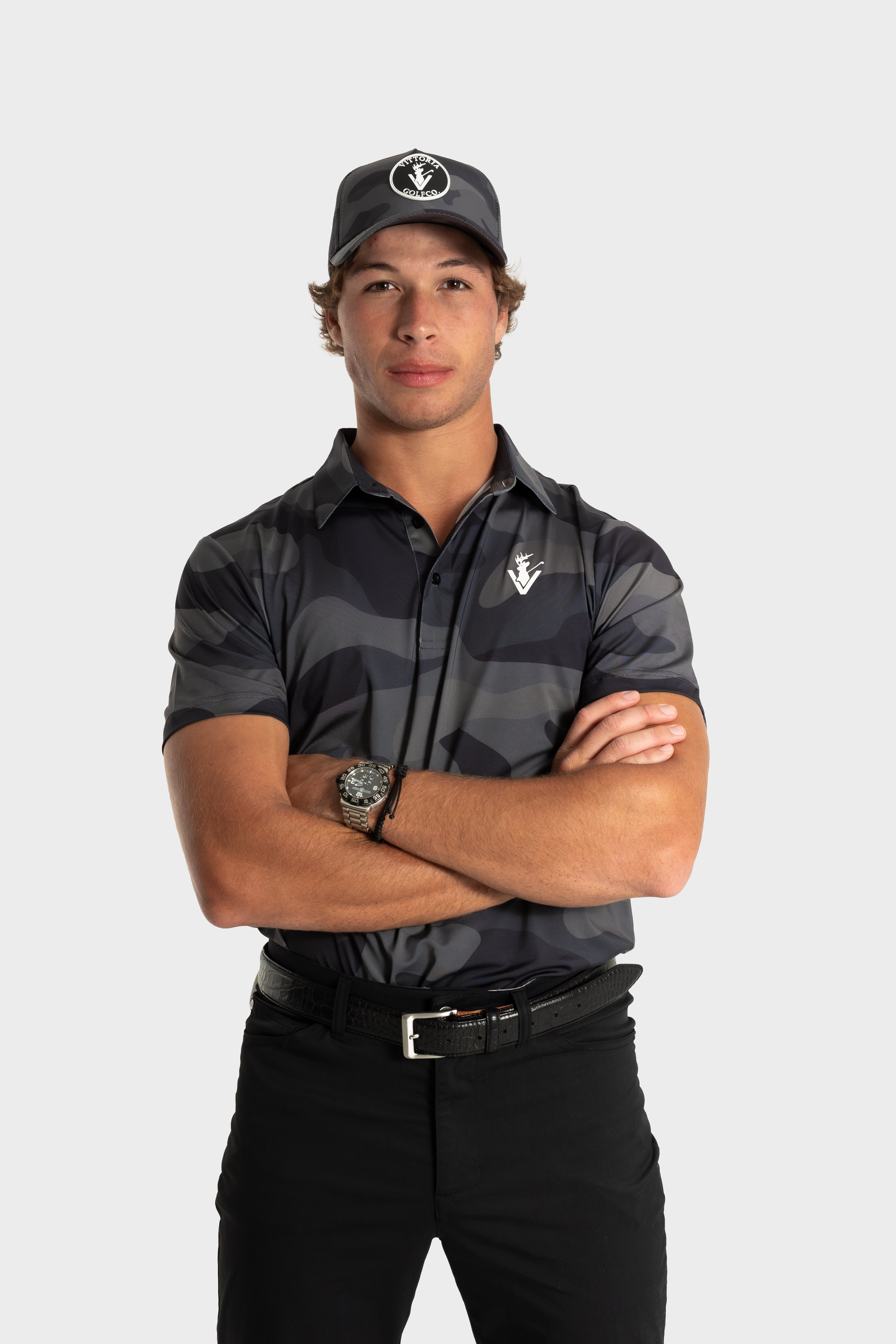 Male model wearing The Invincible polo by VittoriaGolfco with black camo design and matching cap.