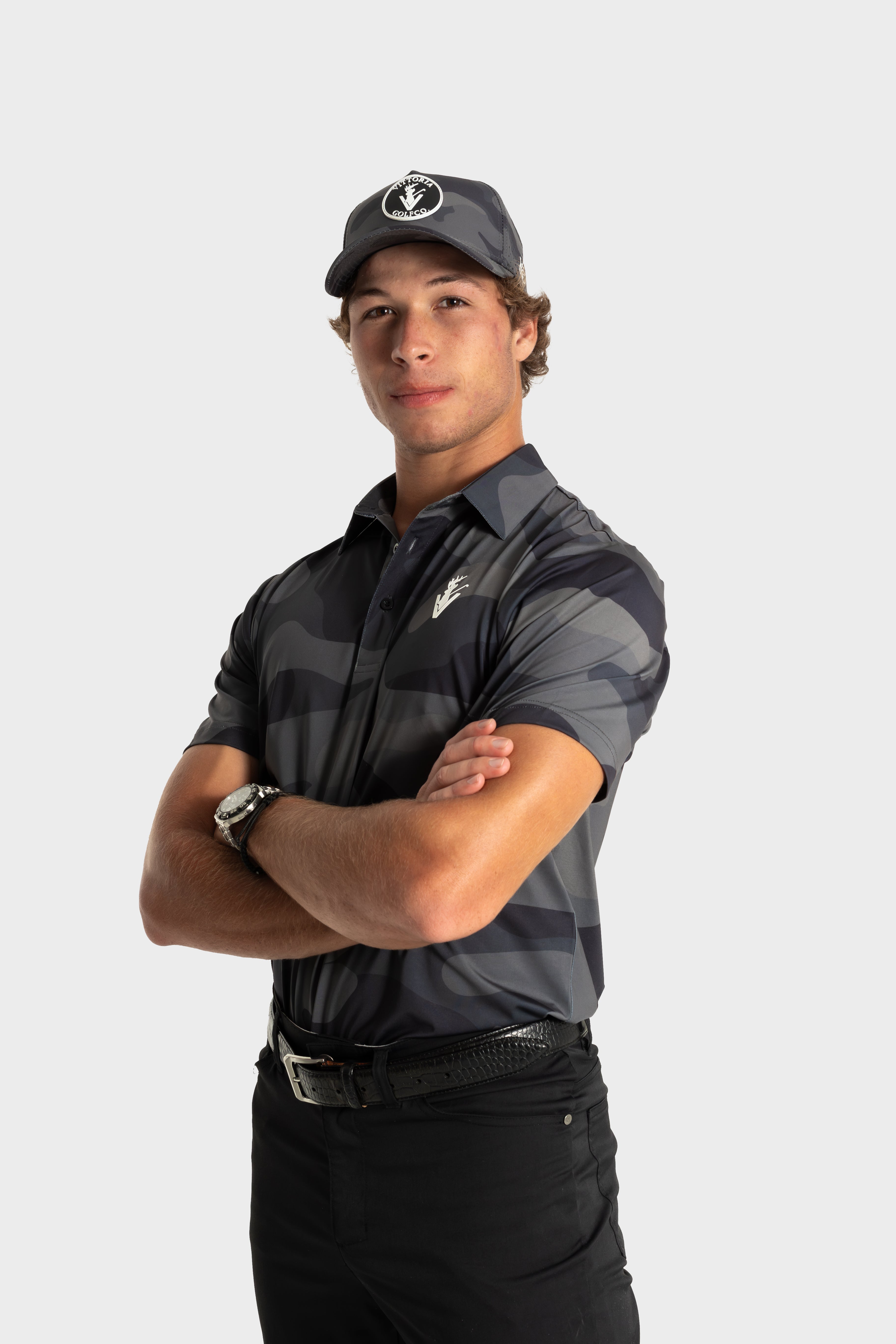 Athlete wearing The Invincible polo by VittoriaGolfco in dark striped design with cap and confident pose