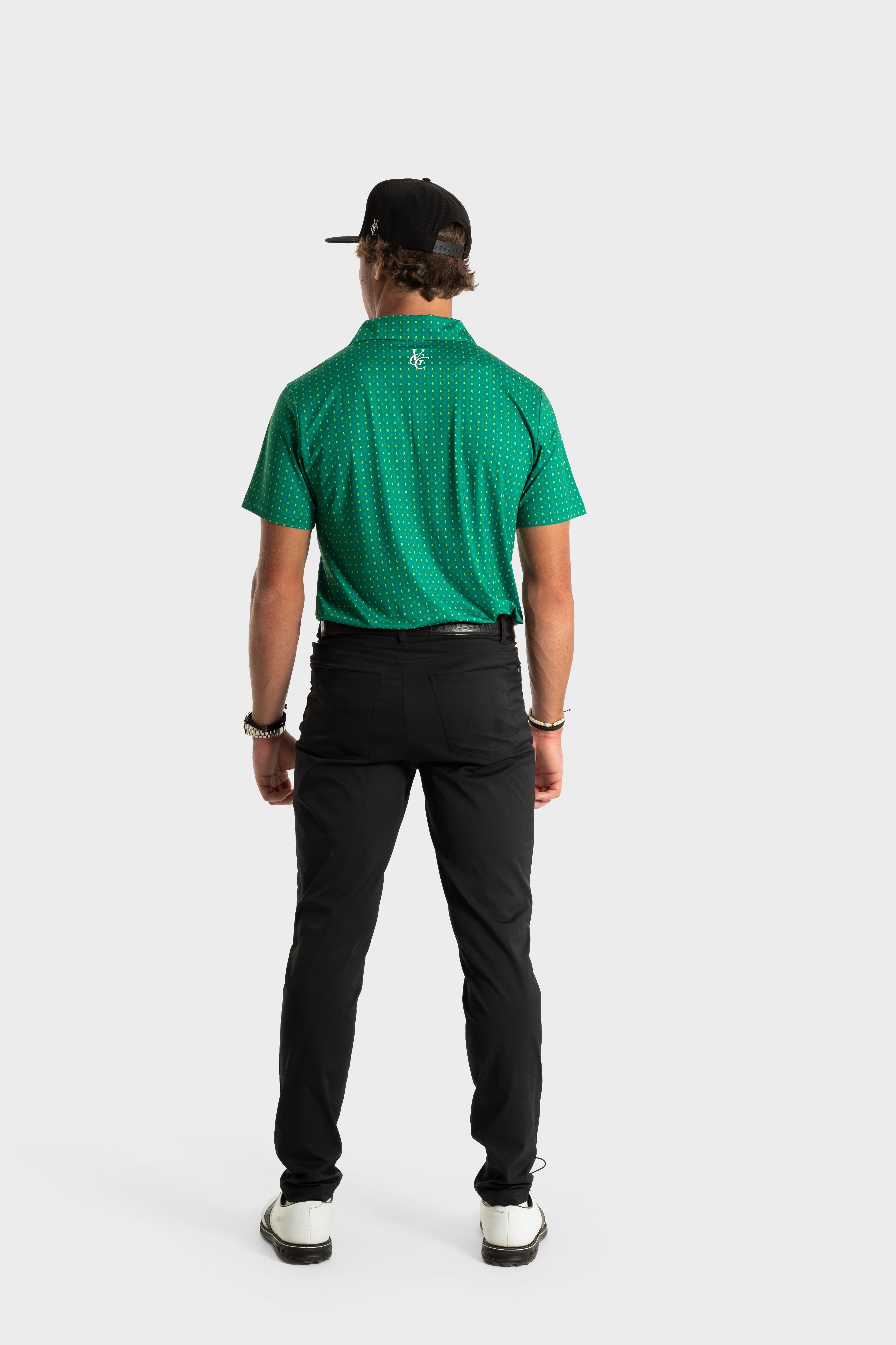 Back view of man wearing green Skullzalea Golf Polo with tiny skull pattern and black pants