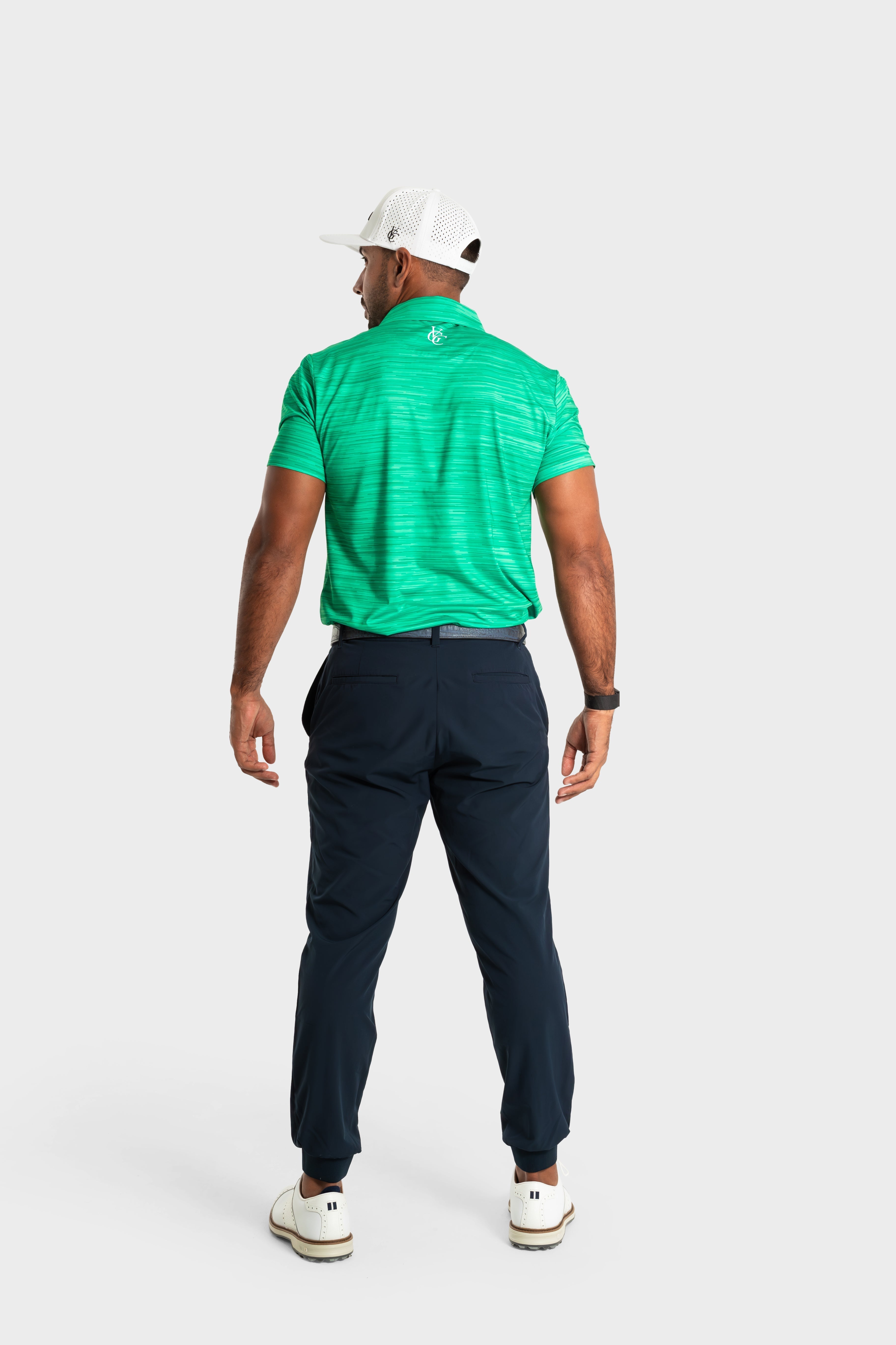 Man wearing The Pasture polo green golf shirt and navy pants viewed from the back