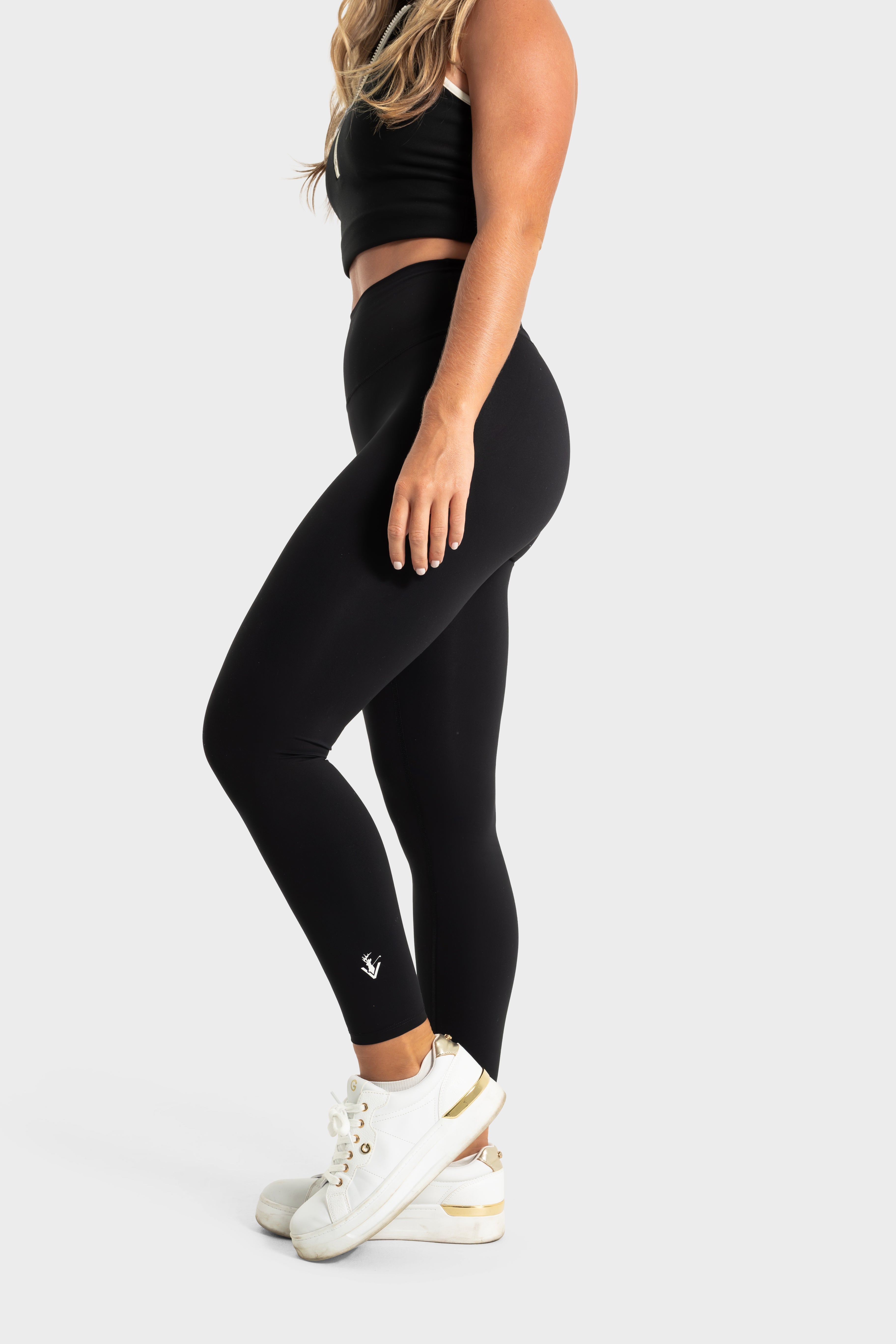 Woman wearing black The Quelles leggings by VittoriaGolfCo showcasing slim fit and stretch fabric