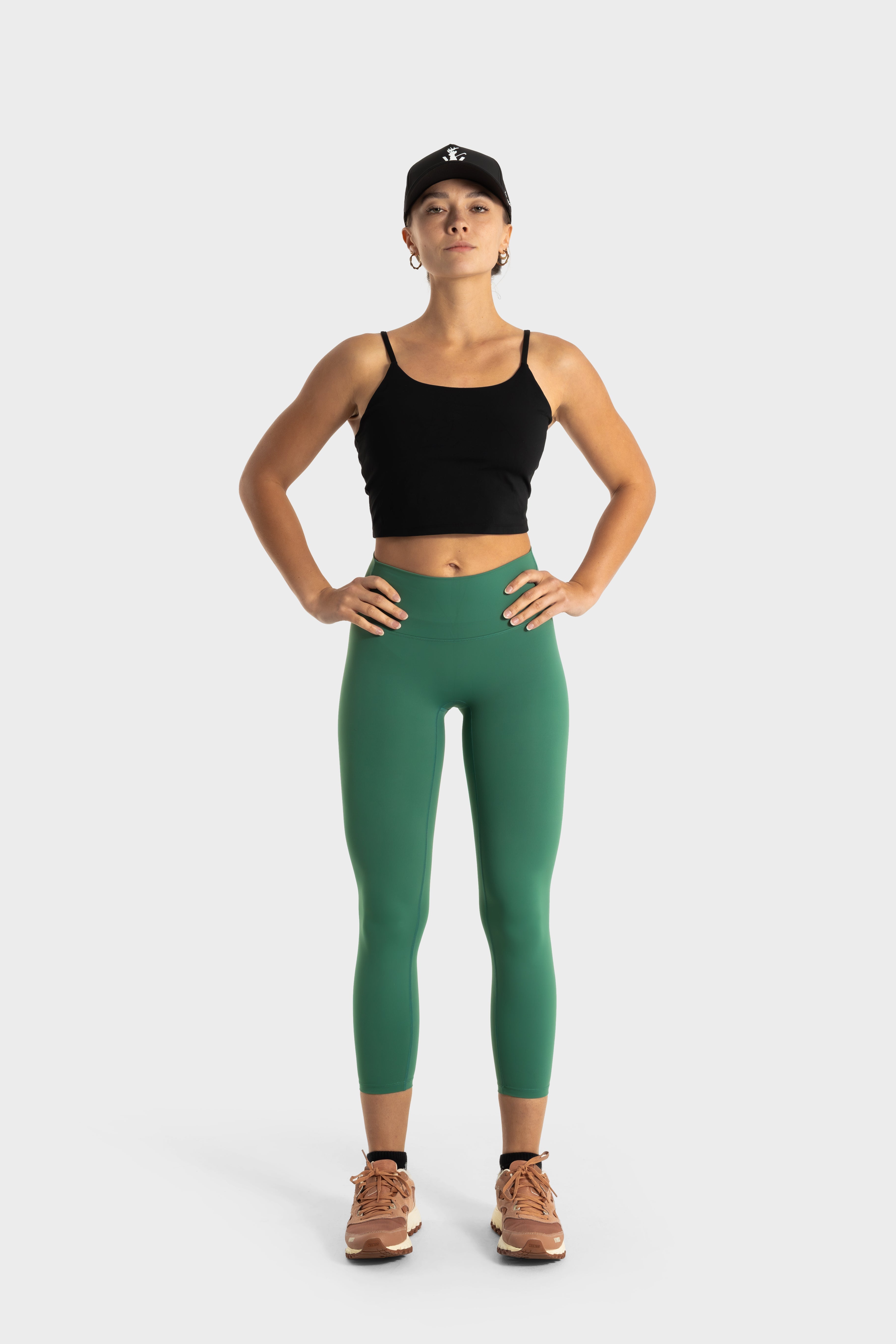 The Quelles green leggings by VittoriaGolfCo modeled by woman in black crop top and cap, showcasing flexibility and comfort.