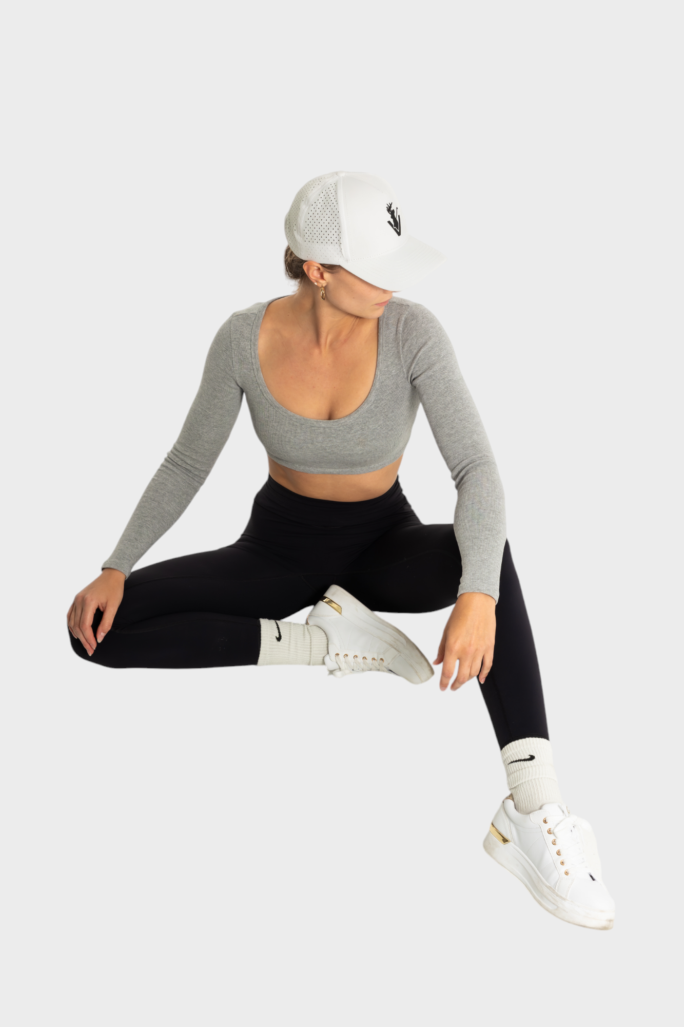 Woman wearing black Sollevare leggings by VittoriaGolfCo with gray crop top and white cap in athletic pose