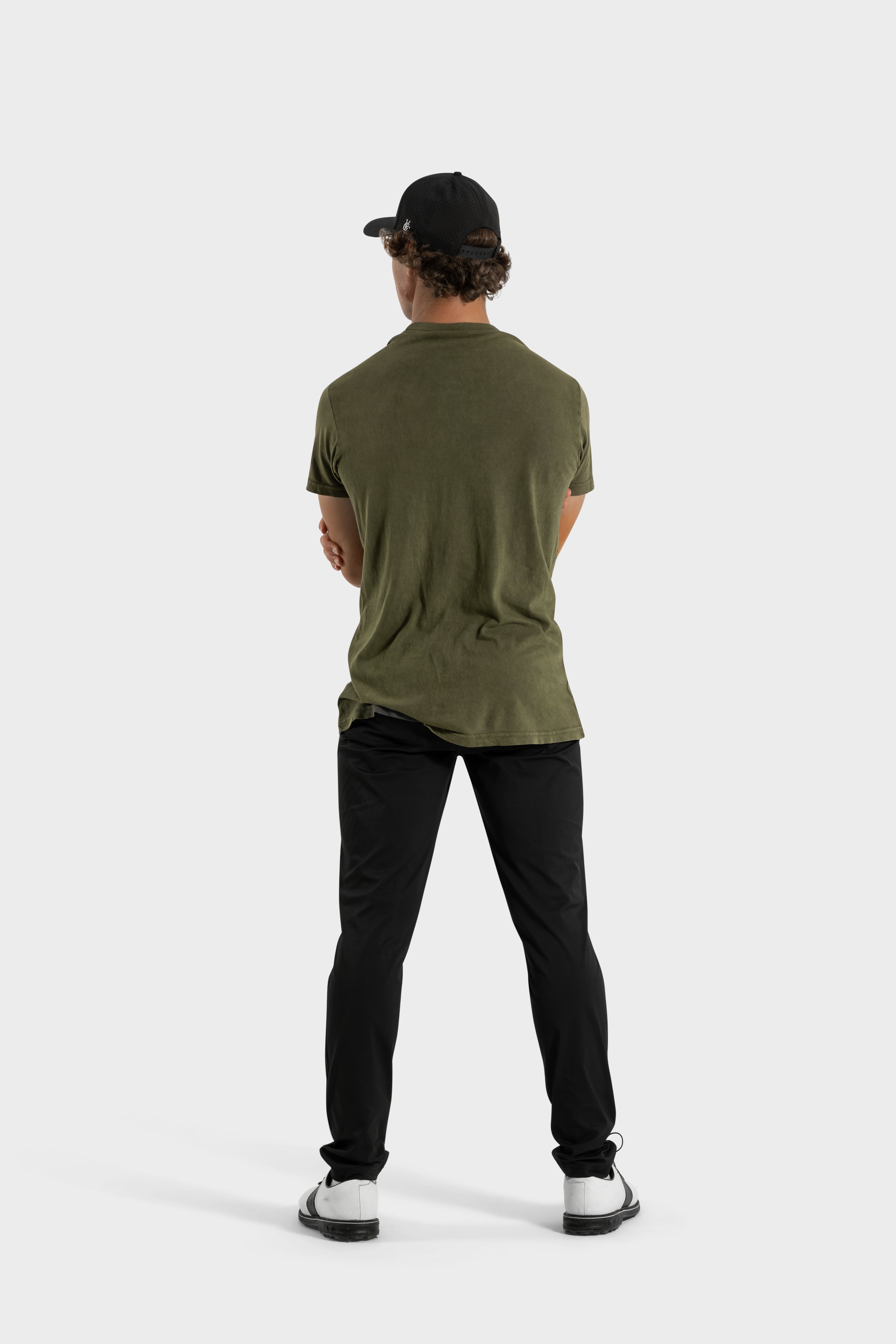 Back view of man wearing Vittoria Oversized Tee in olive green with black pants and cap