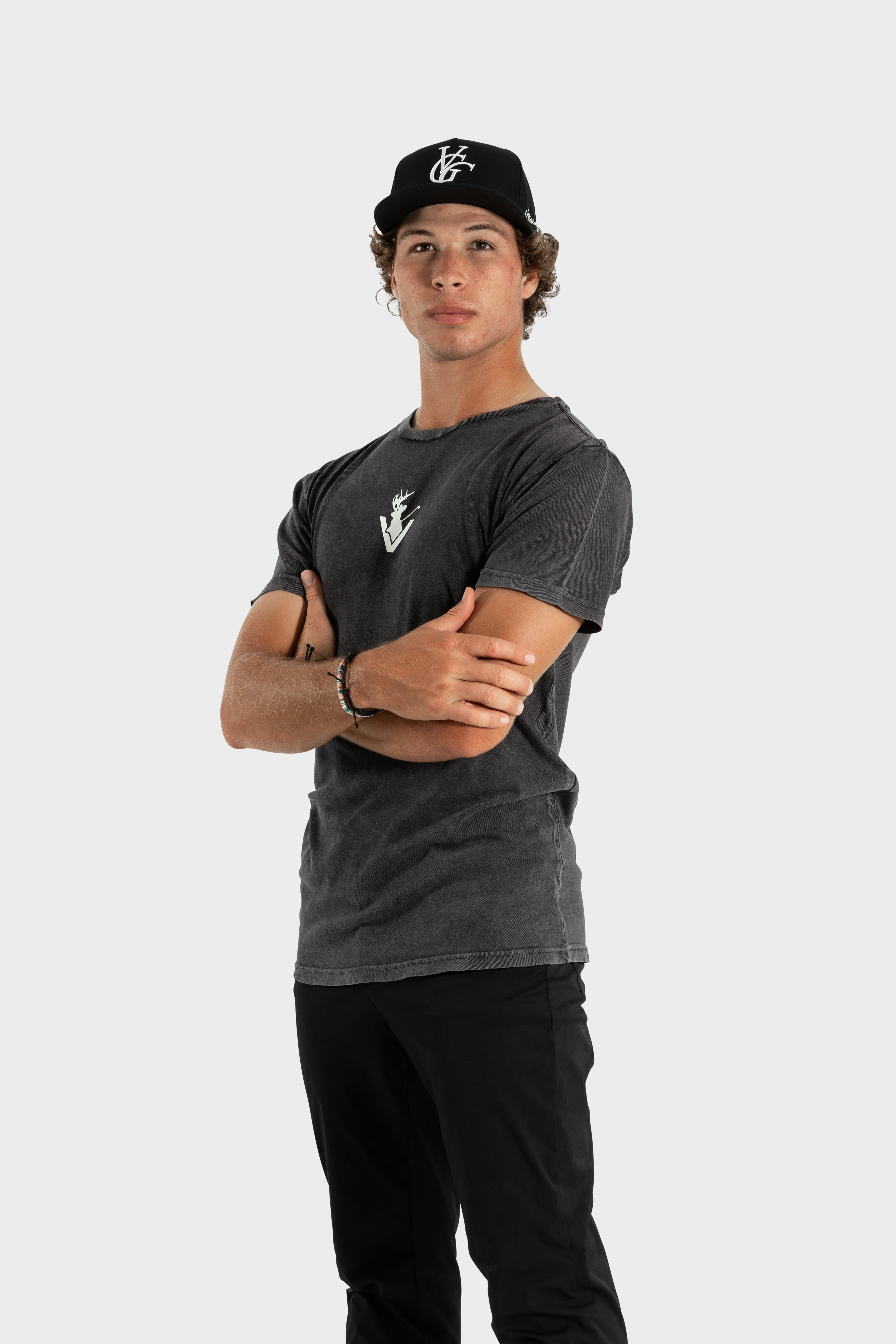 Man wearing black Vittoria Oversized Tee with logo and black cap standing with arms crossed