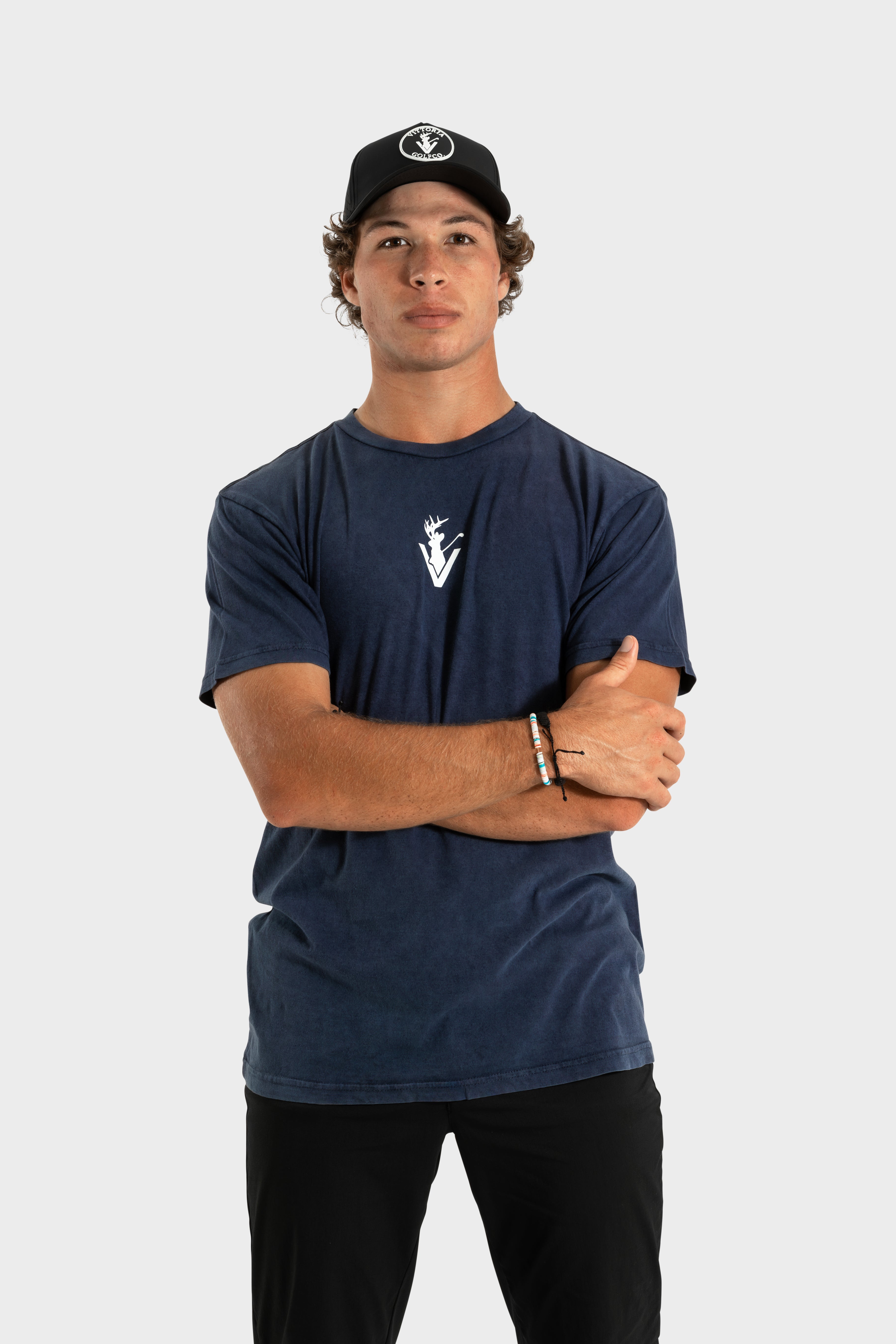 Man wearing navy Vittoria Oversized Tee with logo and black cap against white background