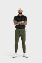 Male model wearing The Nothing polo in black with olive green pants and white golf shoes and cap