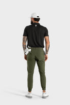 Man wearing The Nothing polo black golf shirt from back with white cap and green pants