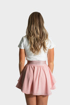 Woman wearing pink Blossom golf skirt by Vittoria Golf Co. with moisture-wicking fabric and built-in compression shorts