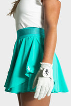 Woman wearing teal Blossom golf skirt and white golf glove in side view