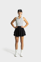 Woman wearing Blossom golf skirt and sporty golf outfit standing confidently against white background