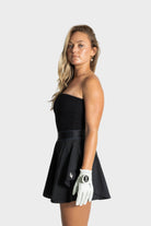 Woman modeling black Blossom golf skirt by Vittoria Golf Co. with golf glove on white background