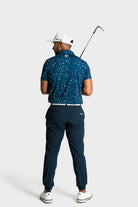 Man wearing The Underlay polo by VittoriaGolfco in blue patterned design holding golf club