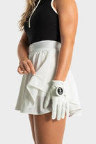 Woman wearing white Blossom golf skirt with built-in shorts and golf glove