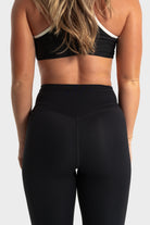 Rear view of woman wearing The Quelles black high-waisted leggings by VittoriaGolfCo with moisture-wicking fabric and flexible fit