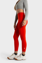 Red Sollevare leggings by VittoriaGolfCo with targeted support and breathable fabric worn with gray crop top and white sneakers