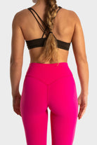 Woman wearing bright pink Sollevare leggings and black strappy sports bra from the back