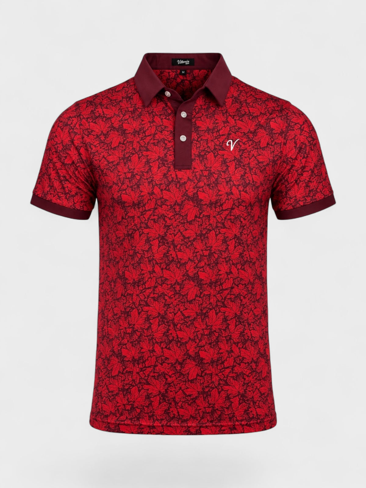 A short-sleeve polo shirt with an all-over red and black floral pattern, featuring a solid dark red collar and placket with white buttons, and a small white embroidered logo on the left chest, shown against a light gray background.