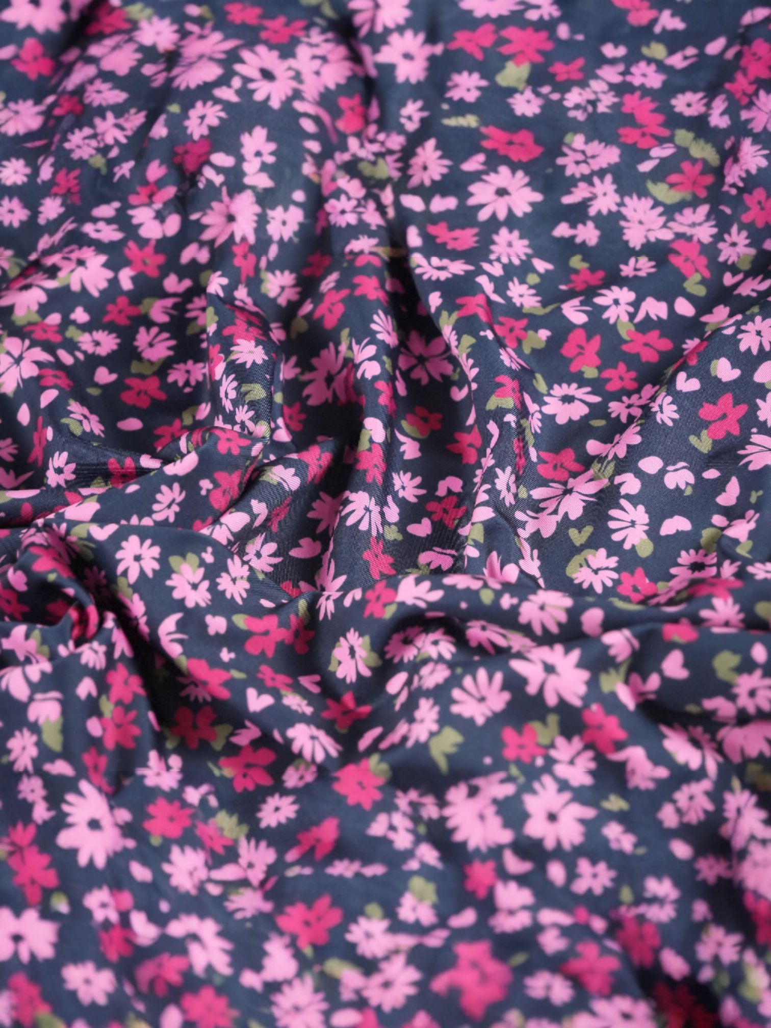 Close-up of fabric with The Secret Garden polo pink and red floral pattern on navy background